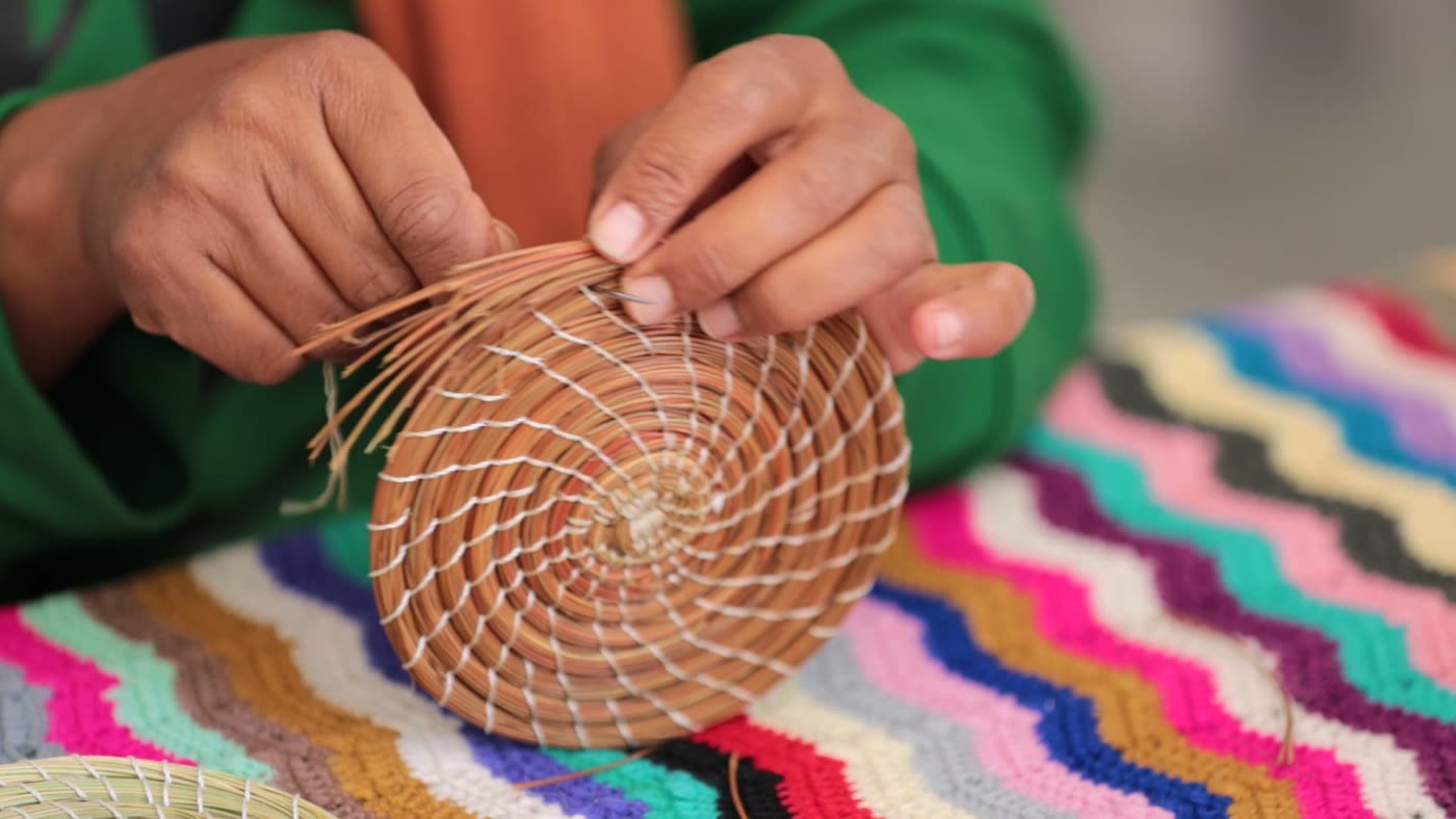 Des mains tressent une spirale d’alfa puis la mesurent