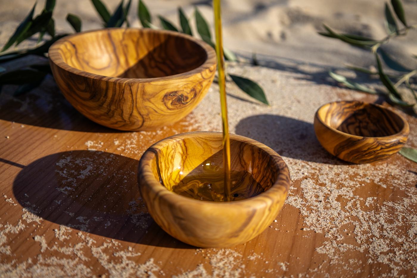 Un filet d’huile d’olive versé dans un bol en bois d’olivier