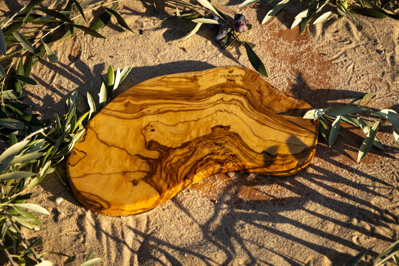 Une planche Garrigue en bois d’olivier, de forme libre, posée dans le sable