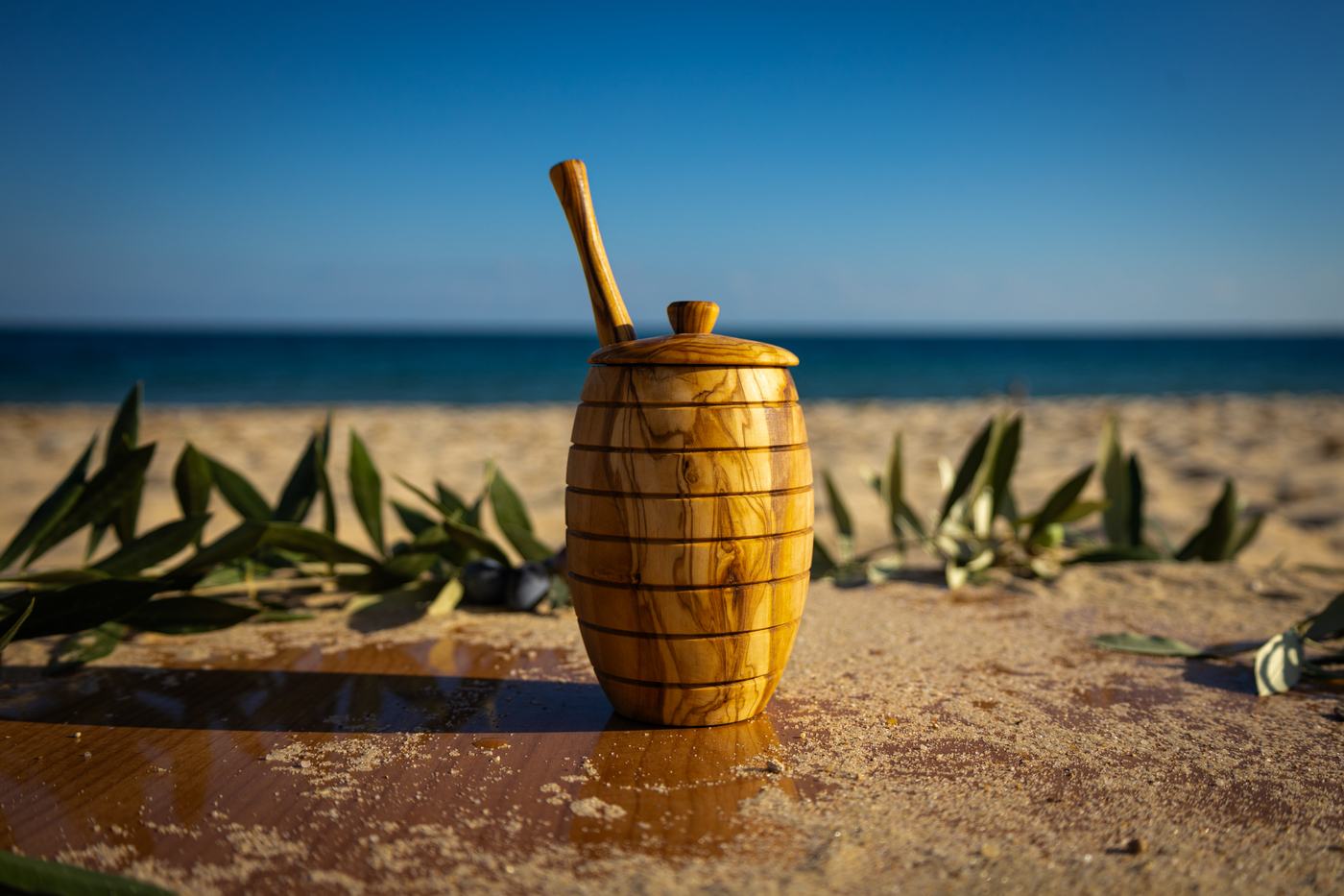 Un pot à miel en bois d’olivier et sa cuillère, face à la mer